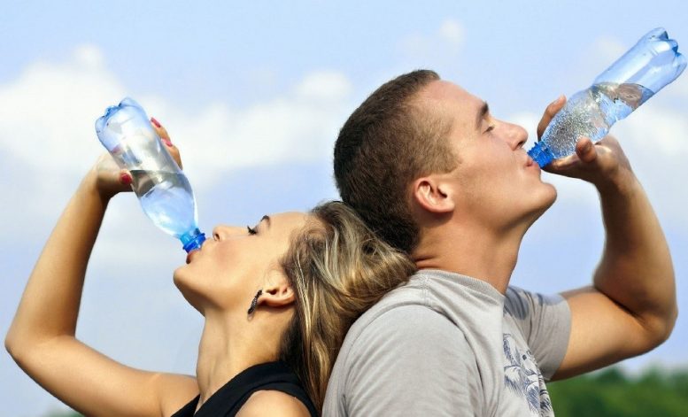 Ilustračný obrázok - foto ľudí, ako pijú vodu. K téme tepla a práce v horúčave